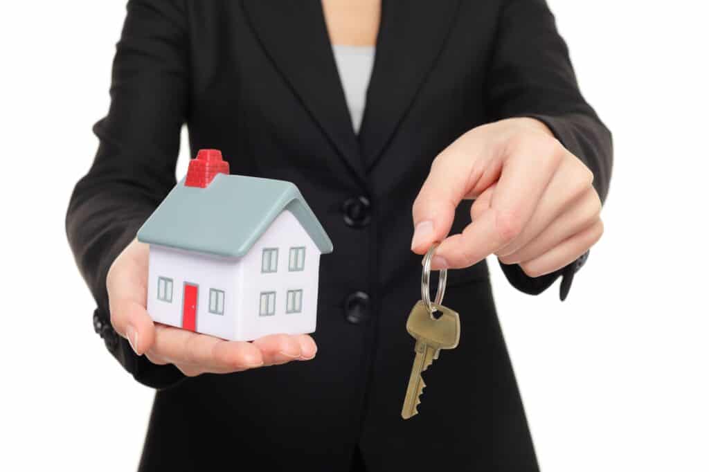 A real estate agent holding a house figurine and a key in the concept of buying a new house