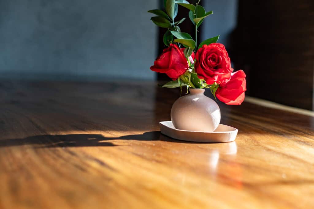 A vase with red roses on top of the dining table