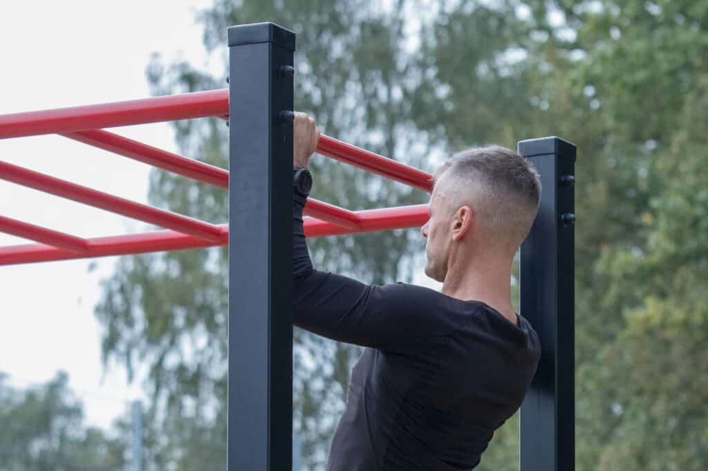 A man doing pull-ups in a park's outdoor gym