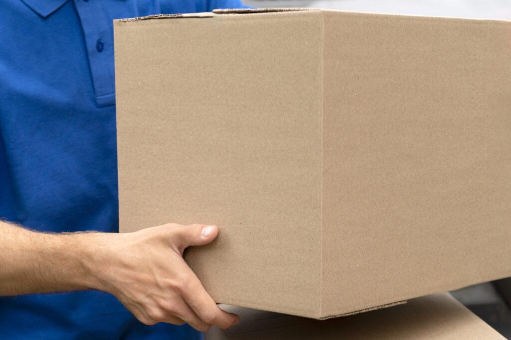 Closeup of carton carried by a mover in the concept of 'the Benefits of Using a Professional Home Removals Service'.